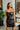 Front view of model wearing the Big Reputation Dress, which features a black faux-leather material, a surplice, sweetheart neckline, a sleeveless design with thin adjustable straps, a draped front, a surplice bottom, and a zip-up back closure