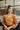Front view of model wearing the Spice It Up Top, which features a camel-colored material, a sweetheart neckline, a long sleeve, a side cut-out with adjustable ties, a smocked back, and a cropped fit