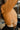 Close-up side view of model wearing the Spice It Up Top, which features a camel-colored material, a sweetheart neckline, a long sleeve, a side cut-out with adjustable ties, a smocked back, and a cropped fit