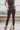 Frontal view of the Next Level Straight Leg Pants that features a black faux-leather material, a high-rise fit, a clasp and zipper front closure, belt loops, two front pockets, a middle seam down the legs, and a straight leg fit.