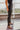 Side view of the Next Level Straight Leg Pants that features a black faux-leather material, a high-rise fit, a clasp and zipper front closure, belt loops, two front pockets, a middle seam down the legs, and a straight leg fit.