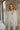 Front view of the Glitz and Glam Blazer features champagne glitter fabric, champagne button closures, low collared neckline, has a lining, left chest pocket and long sleeves.