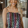 Up close view of the Squared Away Top that features multi color sequin fabric, checkered print, cropped waist, has a lining and spaghetti straps.