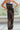Front view of model wearing The Hailey Jumpsuit features black faux-leather, a sleeveless design, a straight neckline, a tie belt at the waist, a back zipper closure, and a straight leg fit.