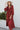 Full body front view of model wearing the Seasons Change Maxi Dress, which has a rust colored fabric, a V neckline, long sleeves, a button-up front, a babydoll design, a midi length, and a flowy fit.