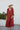 Full body front view of model wearing the Seasons Change Maxi Dress, which has a rust colored fabric, a V neckline, long sleeves, a button-up front, a babydoll design, a midi length, and a flowy fit.