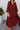 Front view of model wearing the Seasons Change Maxi Dress, which has a rust colored fabric, a V neckline, long sleeves, a button-up front, a babydoll design, a midi length, and a flowy fit.