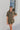 Frontal view of the The Lady May Romper that features an olive green fabric, a collar neckline, a short cuffed sleeve, a button-up front, two front pockets at the chest, a cuffed bottom hem, and two back pockets.