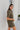 Side view of the The Lady May Romper that features an olive green fabric, a collar neckline, a short cuffed sleeve, a button-up front, two front pockets at the chest, a cuffed bottom hem, and two back pockets.