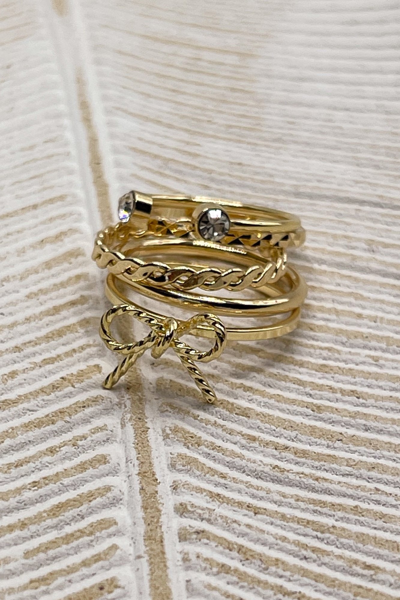 Image shows the Heather Gold Bow Ring Set stacked against a beige background.