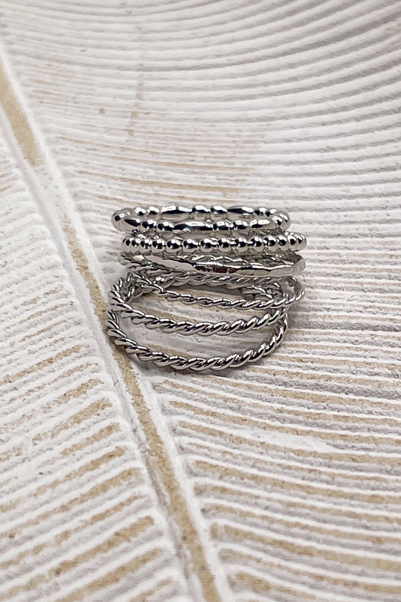 Image shows the Misha Silver Ring Set stacked laying a beige background.