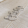 Image shows rings in the Veronica Heart Ring Set in Silver. Rings are in 3 stacks against a beige backdrop.