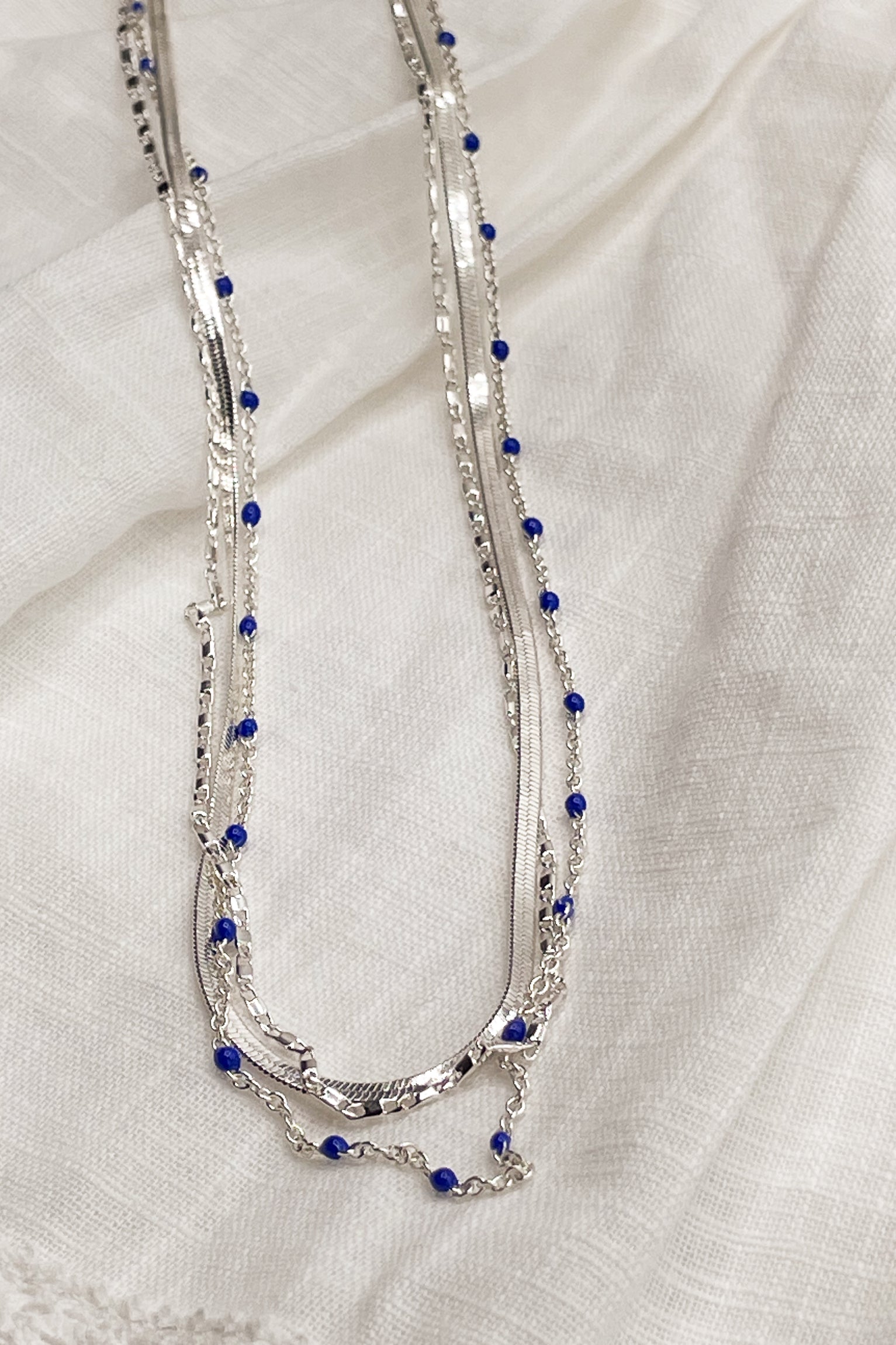 Close up of Kenzie Silver Layered Necklace, silver chain link layer with blue beads.