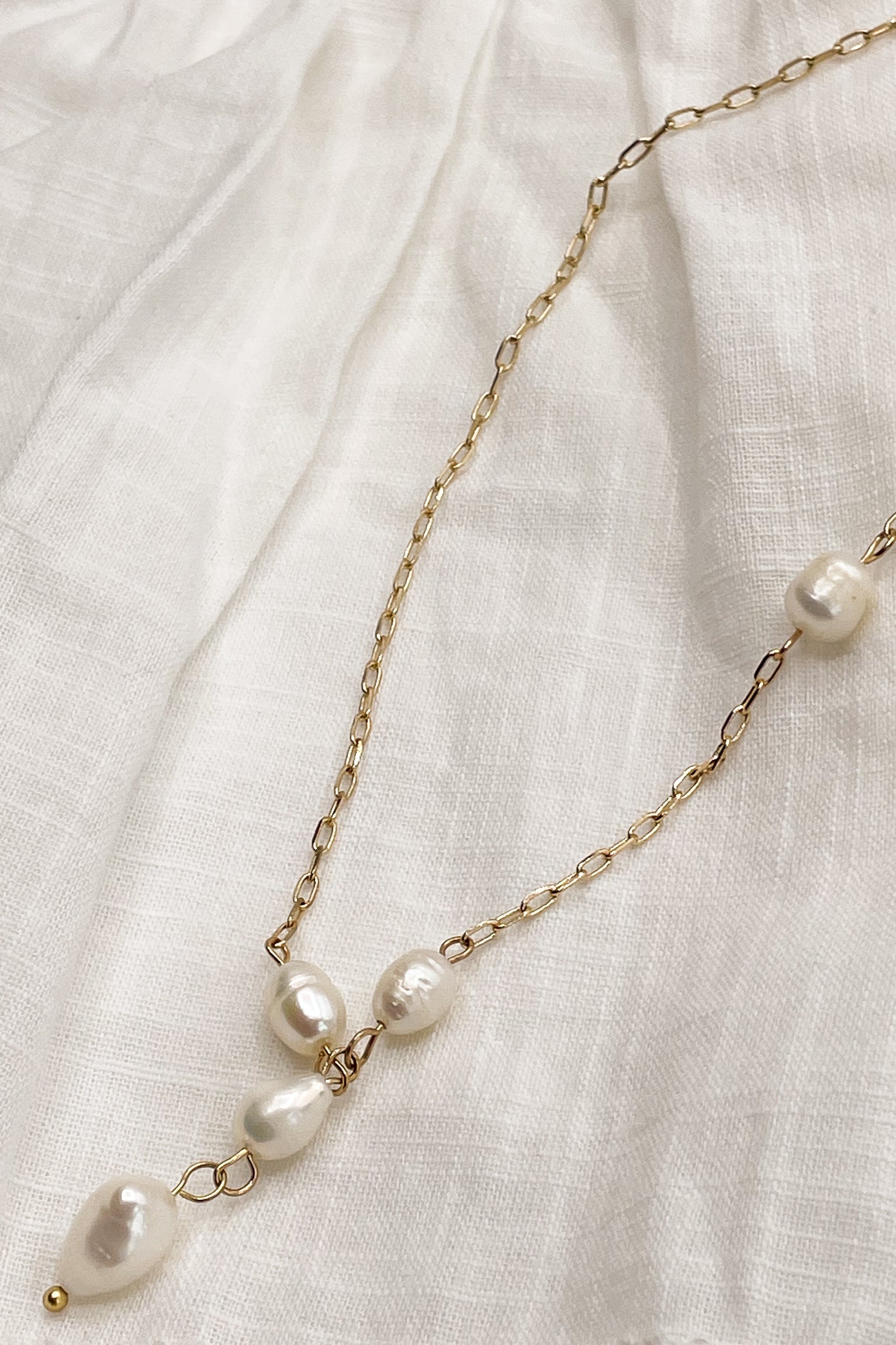 Close up of Nina Pearl Gold Necklace, adjustable gold chain link with pearl beads.