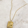 flat lay view of the Orion Sun Gold Necklace which features adjustable gold chain link with rectangle medallion. the medallion says "the sun" with a sun detail