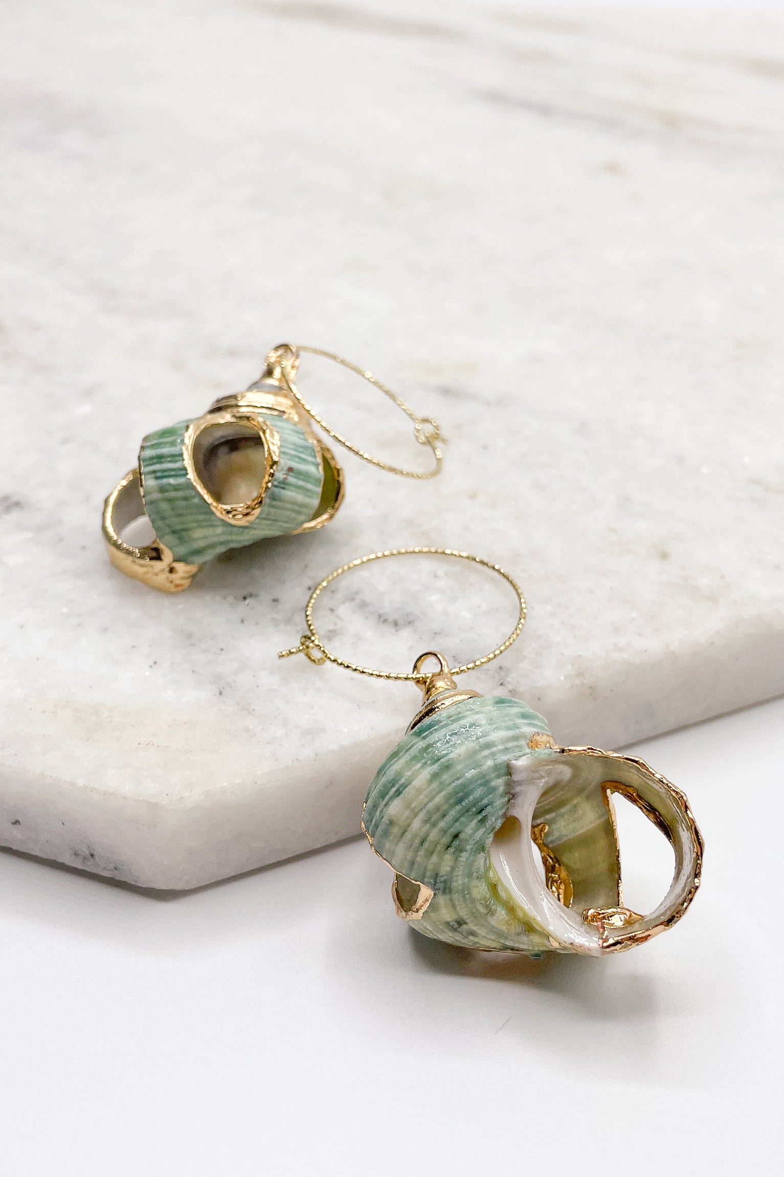 Close up of Diana Green Shell Earrings. These are green seashell earrings with gold accents.