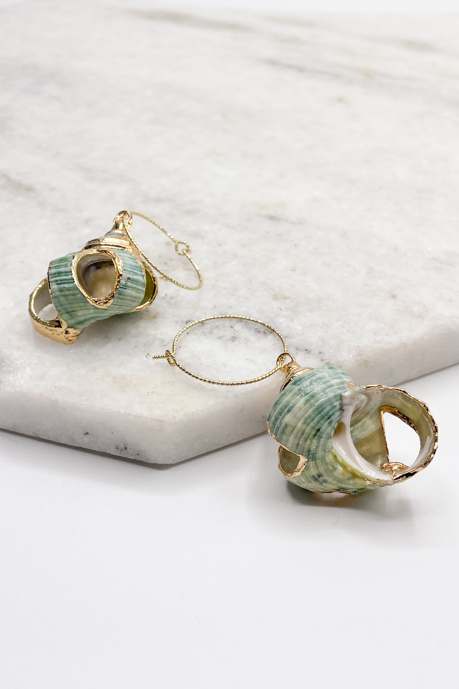 Close up of Diana Green Shell Earrings. These are green seashell earrings with gold accents.