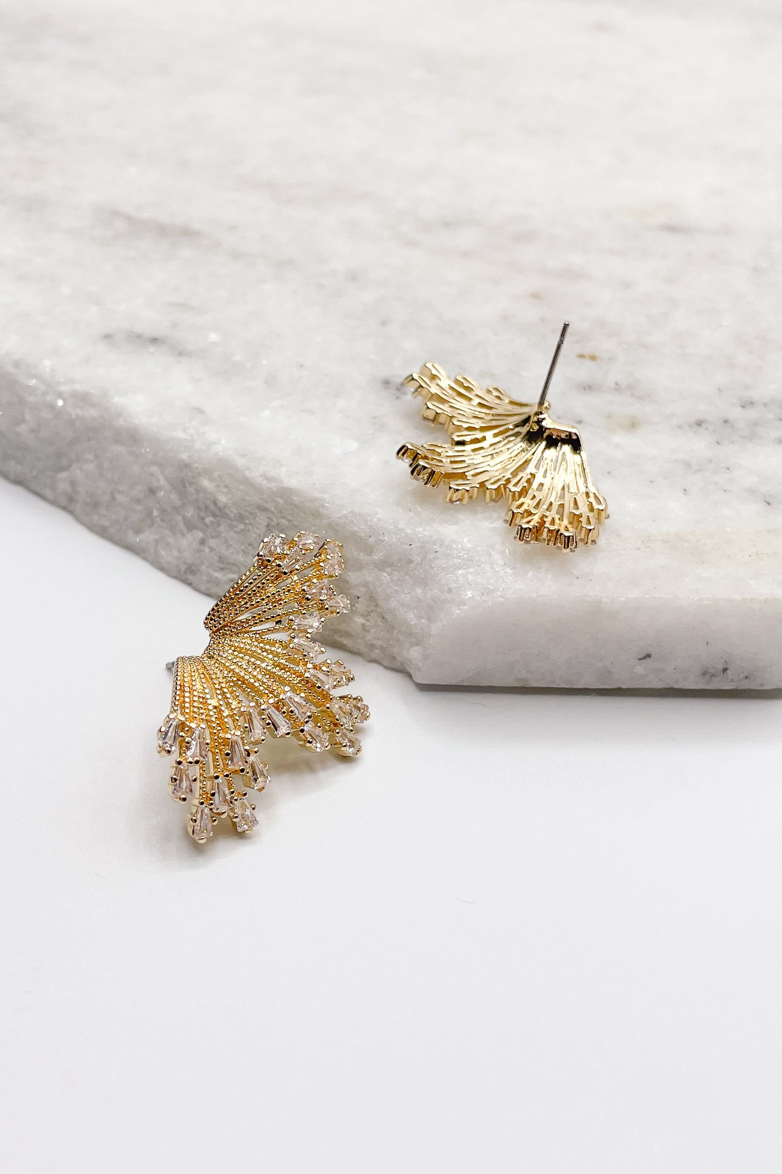 Close up of Valerie Burst Earrings. These are gold burst earrings with clear rhinestones at ends.