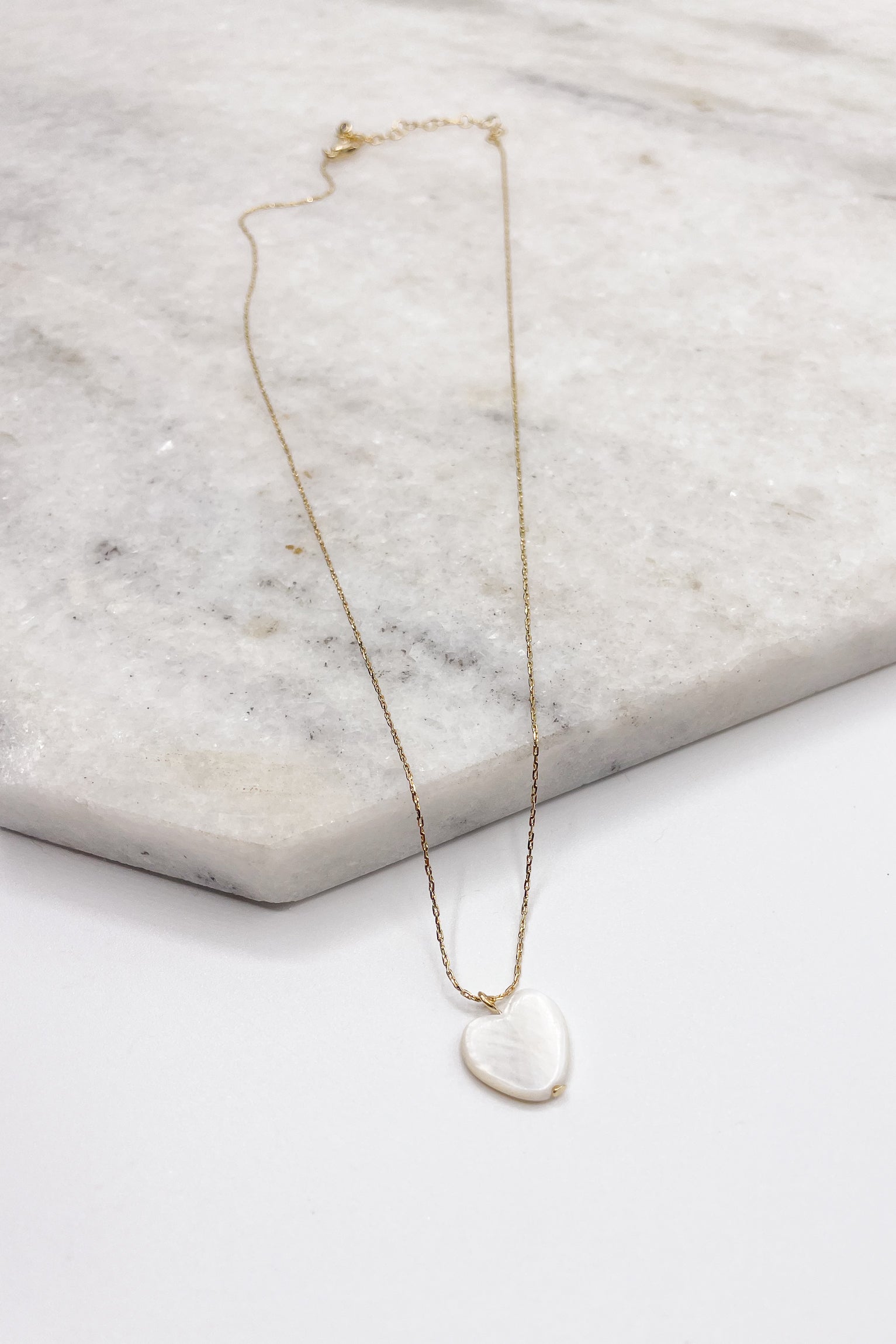 Close up of Skylar Gold Heart Necklace. This is a gold necklace with a white heart.