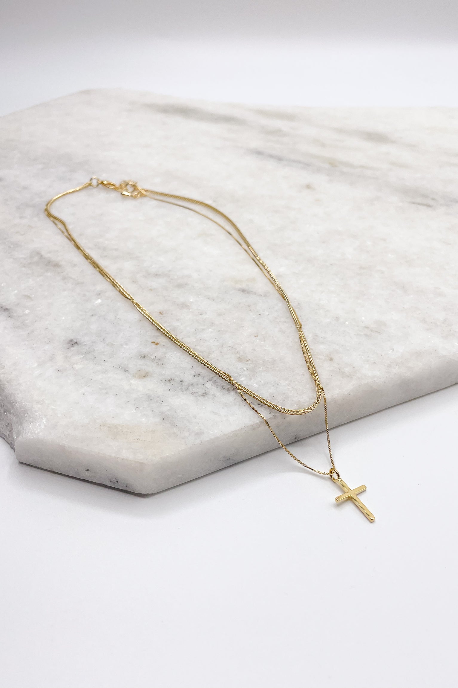 Close up of Eliza Gold Layered Cross Necklace. This is a gold necklace, layered with a cross.