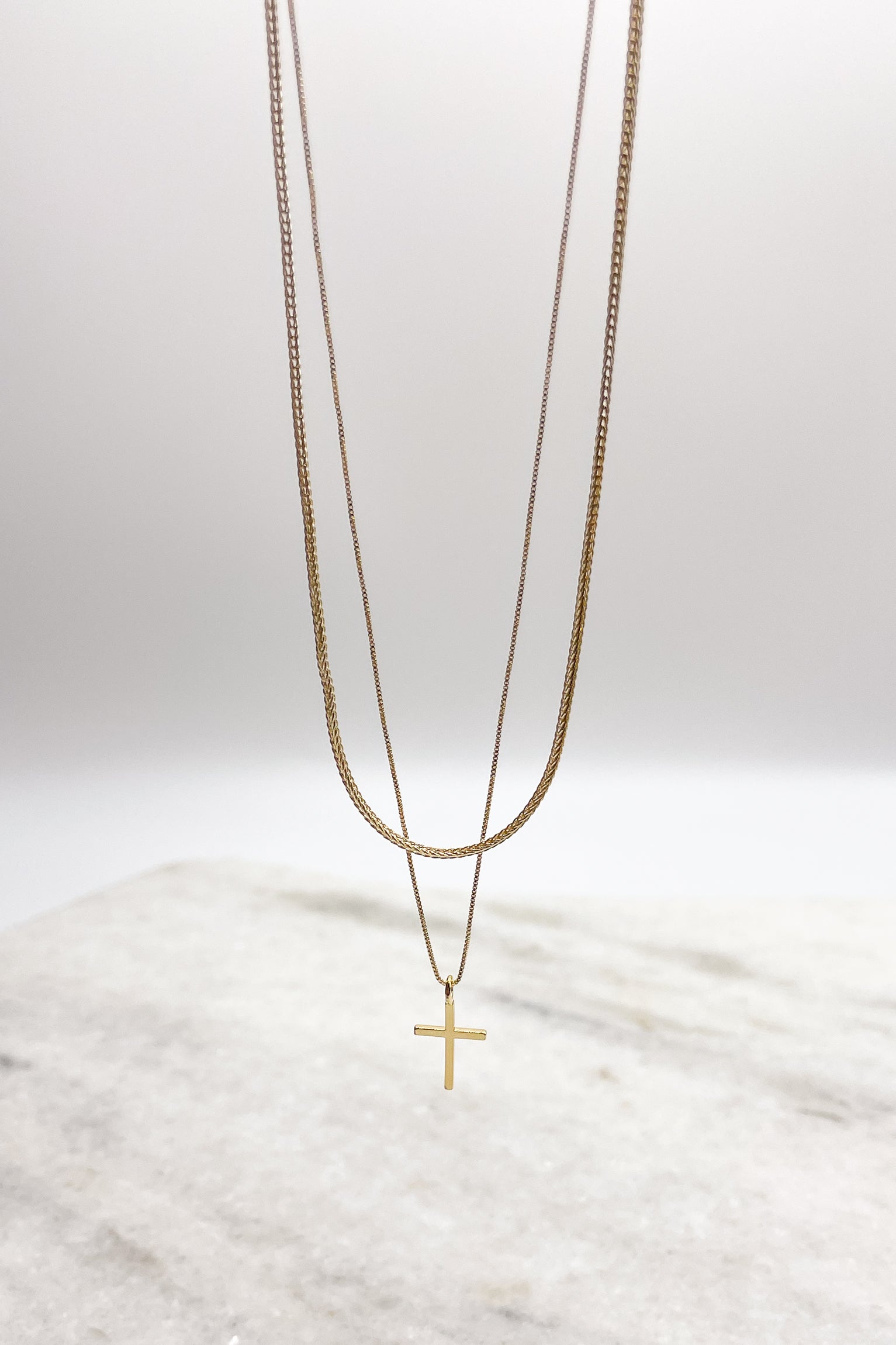 Close up of Eliza Gold Layered Cross Necklace. This is a gold necklace, layered with a cross.