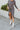 front view of model wearing the Keep Your Cool Dress, which has a grey ribbed material, a round neck, long sleeves, a front knot detail, a front slit, and a high-low silhouette.