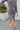 Close-up side view of model wearing the Keep Your Cool Dress, which has a grey ribbed material, a round neck, long sleeves, a front knot detail, a front slit, and a high-low silhouette.