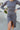 Close-up front view of model wearing the Keep Your Cool Dress, which has a grey ribbed material, a round neck, long sleeves, a front knot detail, a front slit, and a high-low silhouette.