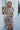 Front view of model wearing the Change of Heart Midi Dress, which features a satin material, a multi-colored floral print, a collared V surplice neckline, short cuffed sleeves, a tie waist, and a midi length