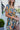 Close-up side view of model wearing the Change of Heart Midi Dress, which features a satin material, a multi-colored floral print, a collared V surplice neckline, short cuffed sleeves, a tie waist, and a midi length