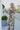 Full body back view of model wearing the Change of Heart Midi Dress, which features a satin material, a multi-colored floral print, a collared V surplice neckline, short cuffed sleeves, a tie waist, and a midi length