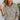 Front view of model wearing the Hamptons Striped Sweatshirt, which features a cream colored material, a black stripe pattern, a rounded green ribbed neckline, and long sleeves with green ribbed cuffs.