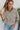 Front view of model wearing the Hamptons Striped Sweatshirt, which features a cream colored material, a black stripe pattern, a rounded green ribbed neckline, and long sleeves with green ribbed cuffs.