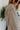 Close-up side view of model wearing the Hamptons Striped Sweatshirt, which features a cream colored material, a black stripe pattern, a rounded green ribbed neckline, and long sleeves with green ribbed cuffs.