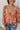 Close-up front view of model wearing the Take Me Back Floral Top, which features a chiffon material, a multi-colored floral print, a V neckline with a tie detail, a front cut-out, long sleeves, and a smocked back