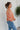 Side view of model wearing the Take Me Back Floral Top, which features a chiffon material, a multi-colored floral print, a V neckline with a tie detail, a front cut-out, long sleeves, and a smocked back