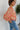 Side view of model wearing the Take Me Back Floral Top, which features a chiffon material, a multi-colored floral print, a V neckline with a tie detail, a front cut-out, long sleeves, and a smocked back