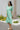 Full body side view of female model wearing the Celeste Green & Cream Floral Paisley Midi Dress which features Green and Cream Floral Paisley Pattern, Midi Length, Tiered Body, V-Neckline with Collar and Short Puff Sleeves