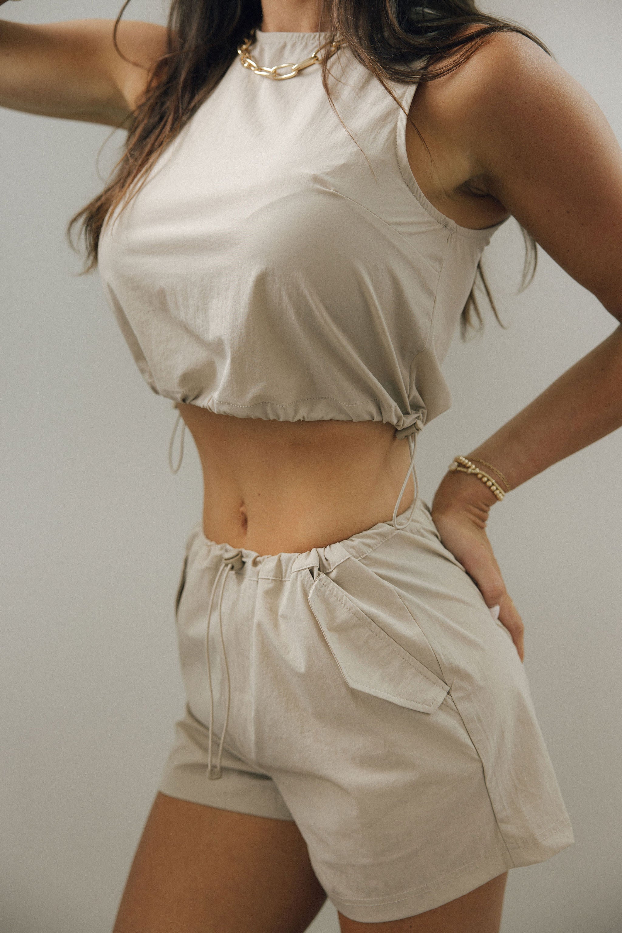 Close up side view of female model wearing the Ari Light Taupe Drawstring Shorts which feature Light Taupe Lightweight Fabric, Two Side Pockets and Adjustable Drawstring Waistband