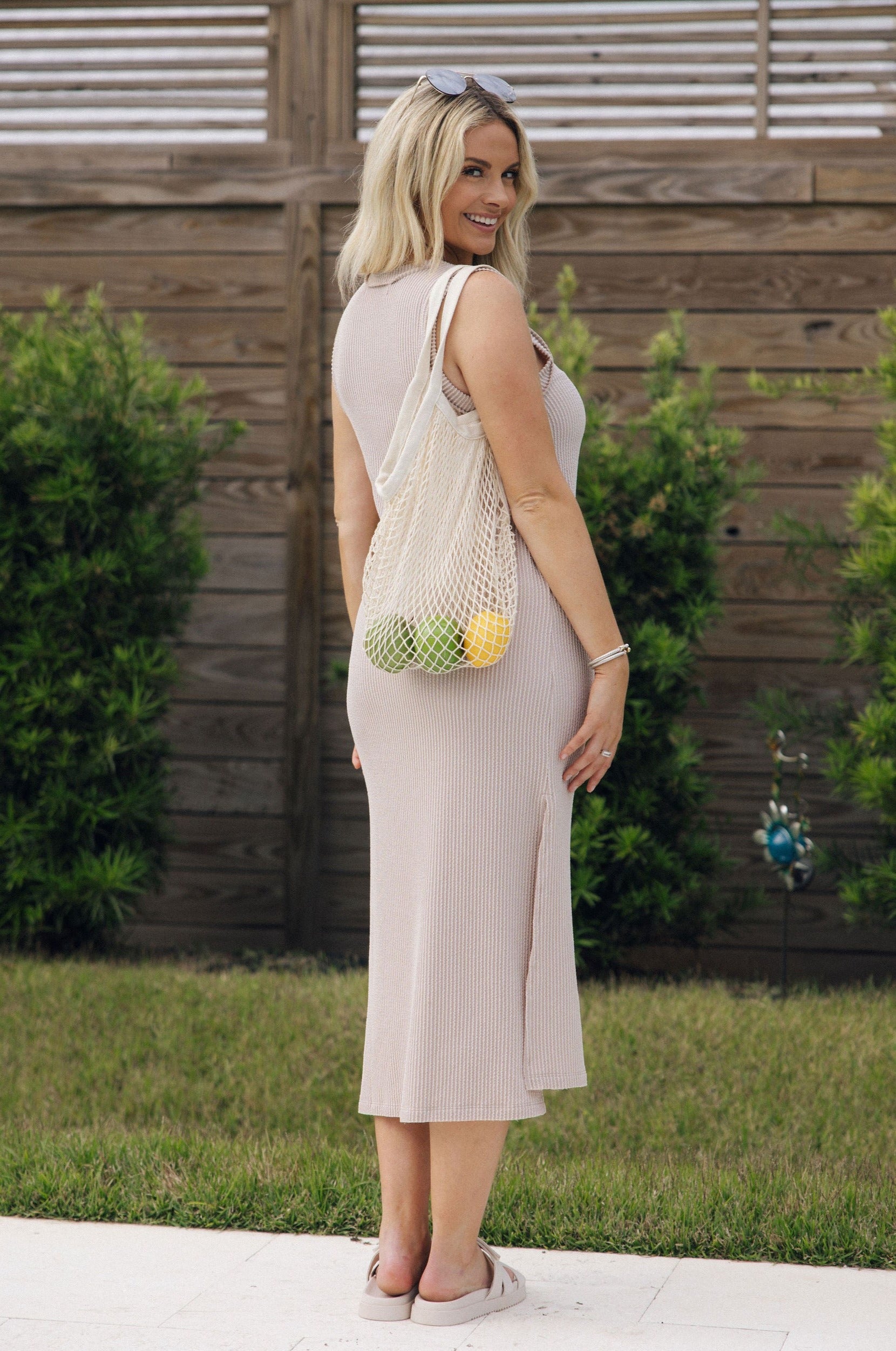 Full body back view of female model wearing the Everly Light Taupe Ribbed Sleeveless Midi Dress which features Light Taupe Ribbed Fabric, Midi Length, Slit On The Side, Round Neckline and Sleeveless