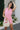 Front view of female model wearing the Palmer Pink Ruffle Halter Sleeveless Romper which features Pink Lightweight Fabric, Pink Shorts Lining, Surplice Neckline with Halter Neck Ties, Ruffle Hem Details, Open Back and Back Zipper with Hook Closure