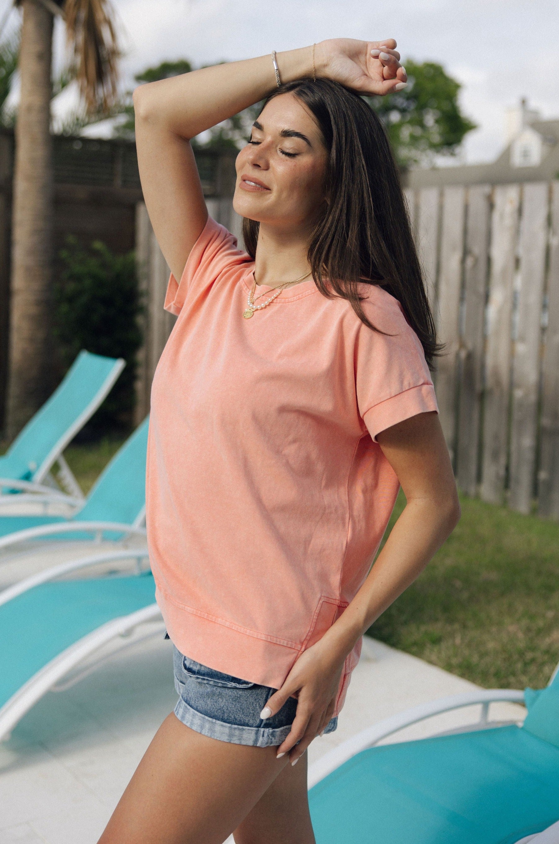 Side view of female model wearing the Jane Peach Short Sleeve Top which features Peach Cotton Fabric, Slits on each side, Short Sleeves and Round Neckline