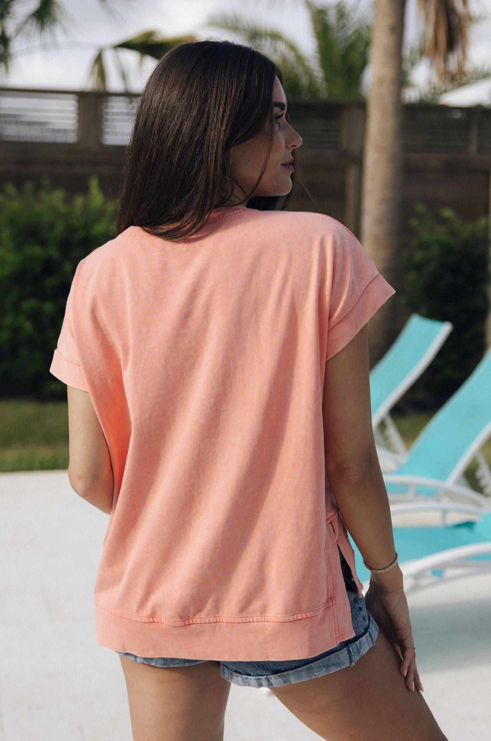 Back view of female model wearing the Jane Peach Short Sleeve Top which features Peach Cotton Fabric, Slits on each side, Short Sleeves and Round Neckline