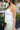 Upper body side view of female model wearing the Lana White Tiered Tank Top that has white textured fabric, a sweetheart neck, thin straps, and a tiered body.