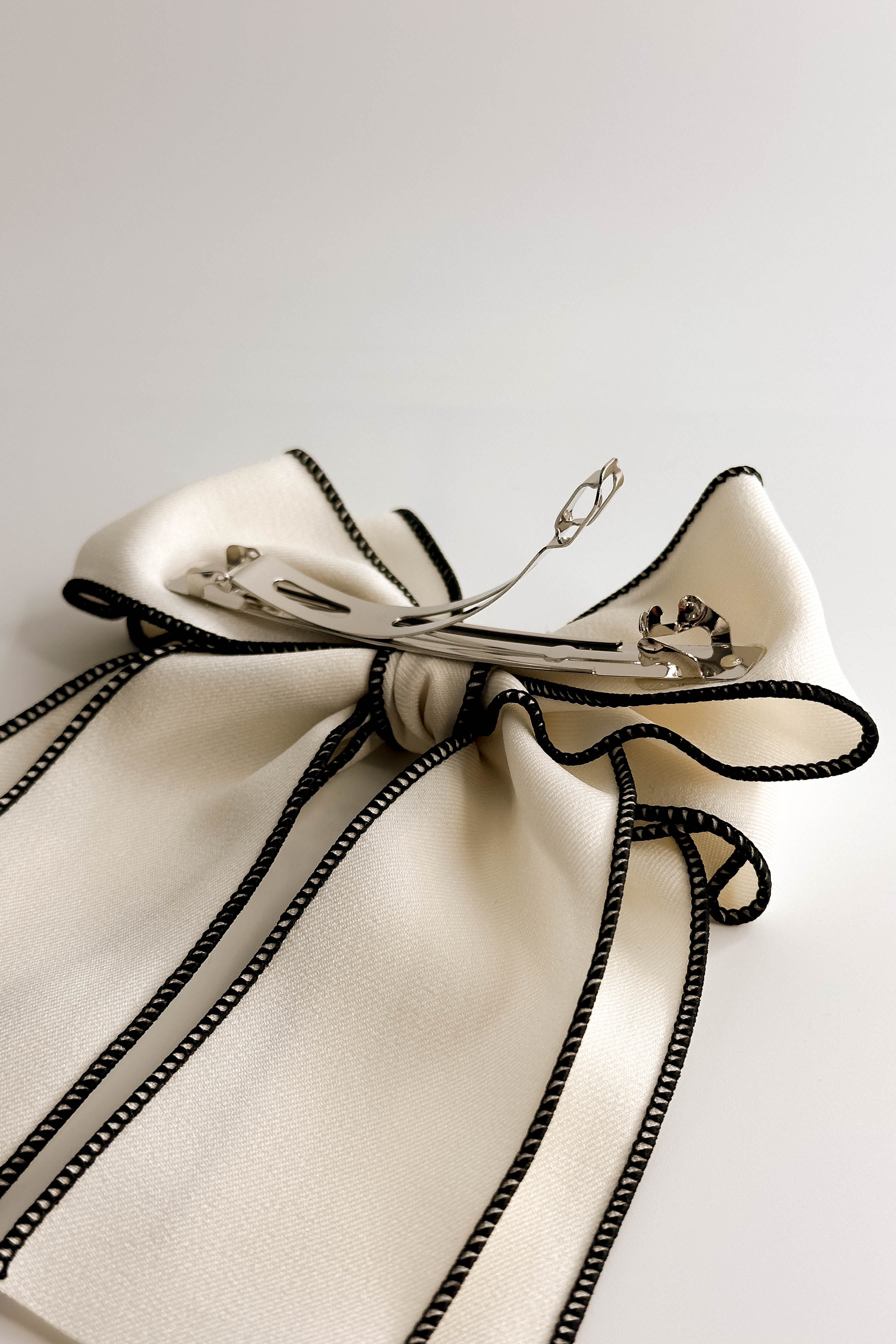 Back view of Felicity Hair Bow Barrette in Ivory/Black which features ivory fabric with black fabric trim, double bow with a french barrette clip