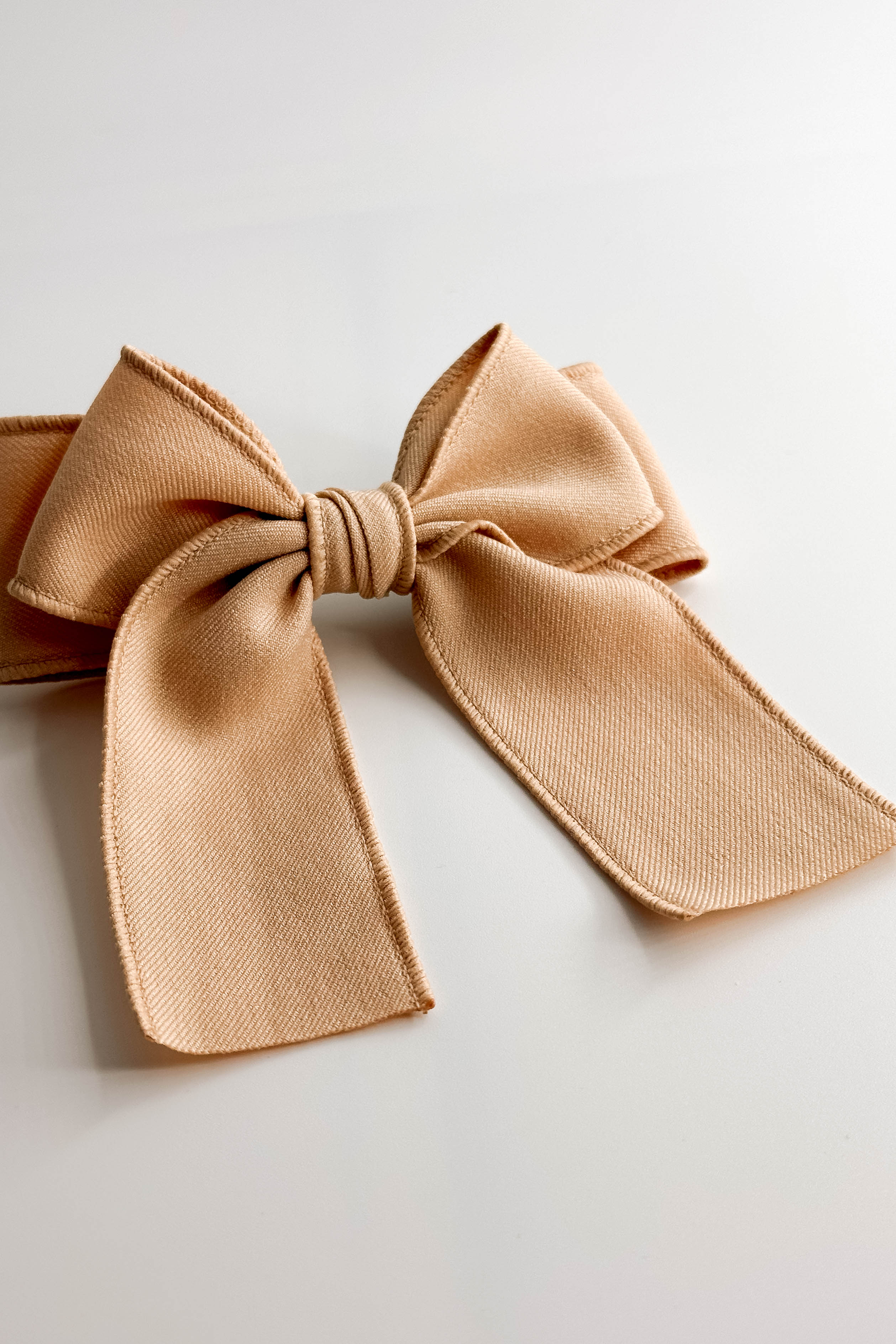 Front view of the Olivia Hair Bow Barrette in Beige which features beige fabric, double bow with a french barrette clip