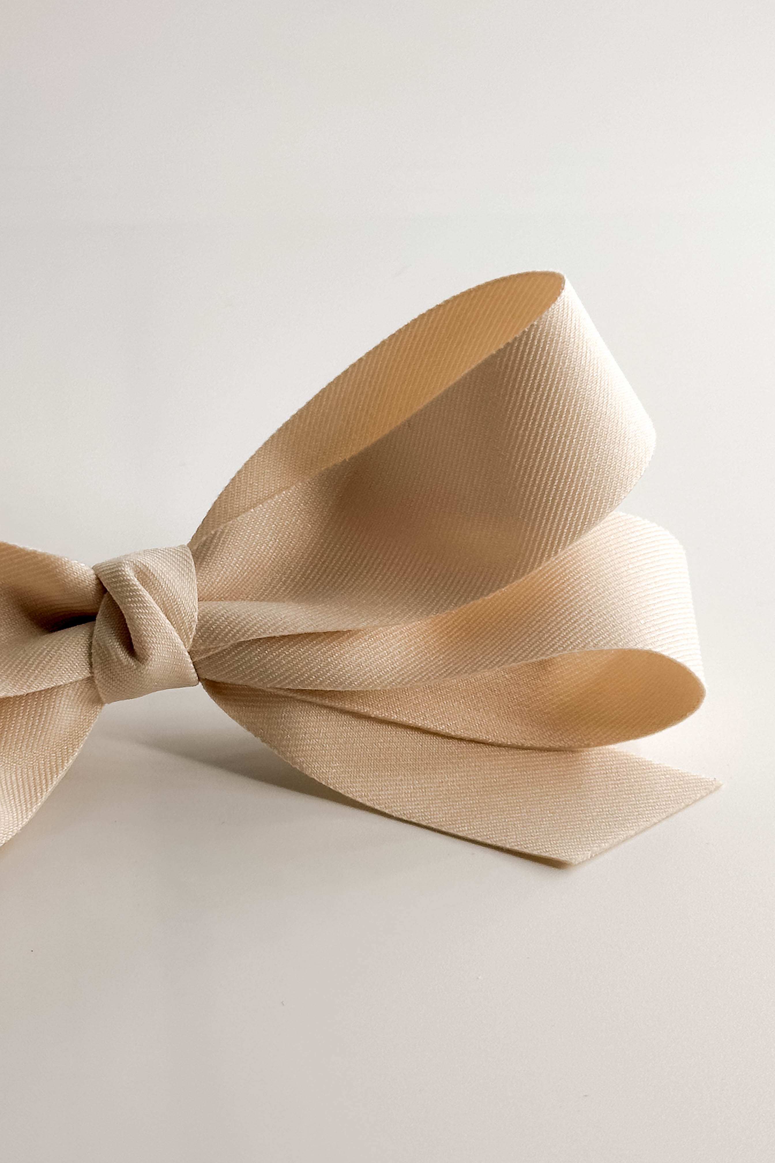Close up view of Luna Hair Bow Barrette in Ivory which features small ivory, double bow with a french barrette clip