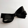 Flat lay of Luna Hair Bow Barrette in Black which features small ivory, double bow with a french barrette clip