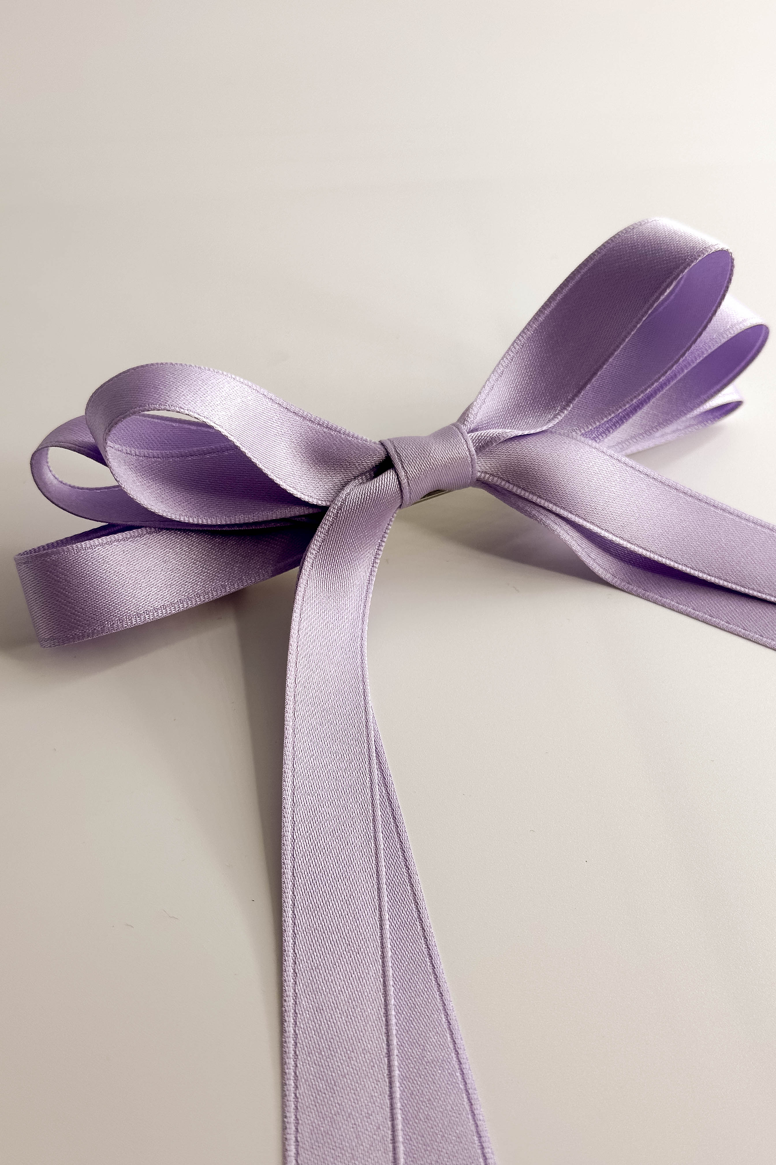 Close up view of Camila Satin Hair Bow Barrette in Lavender which features lavender, triple bow with a french barrette clip.