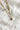 Close up view of the Celeste Gold Triple Layer Chain Heart Necklace which features two gold chain link layers, rhinestone layer, gold heart medallion and set in golds